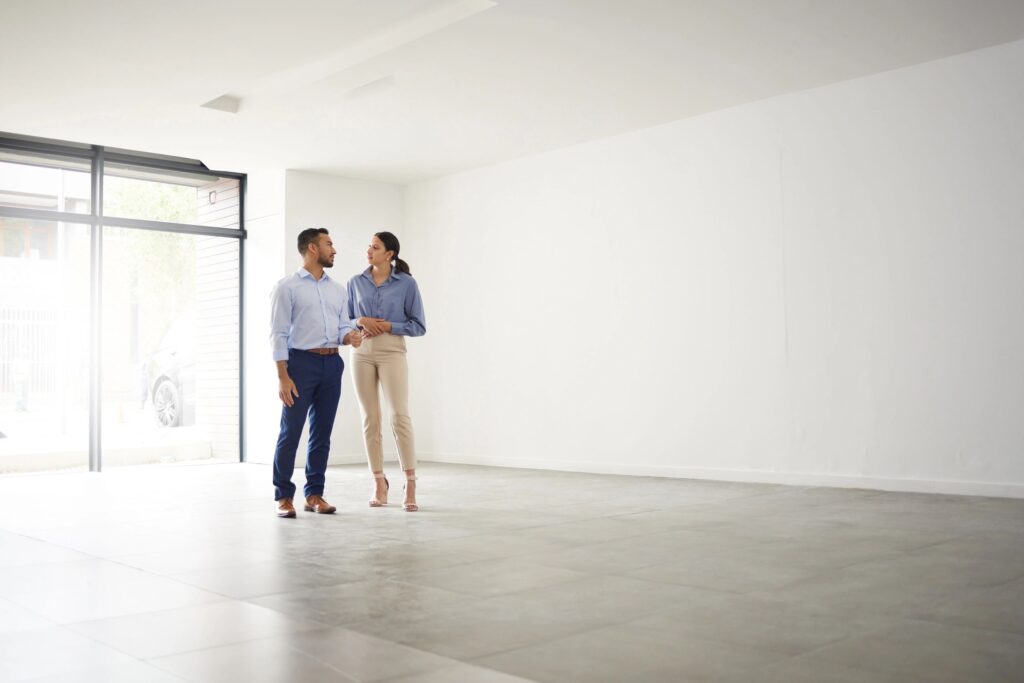 Well-dressed man and woman discussing in an empty, bright Idaho property with floor-to-ceiling windows, symbolizing Boise estate sales and inherited home guidance.