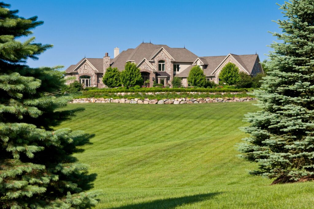 Large Idaho mansion with manicured front lawn and evergreen trees.