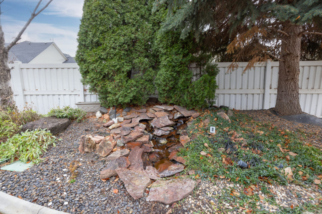 Backyard view featuring mature landscaping, a disappearing stream, and vinyl fence at 2680 south loftus way in meridian, idaho listed by jeff sudmeier with idahoreal.estate team at action real estate.