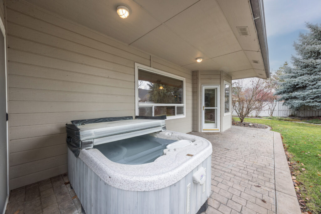 Backyard patio view featuring mature landscaping, stamped concrete patio, and hot tub at 2680 south loftus way in meridian, idaho listed by jeff sudmeier with idahoreal.estate team at action real estate.