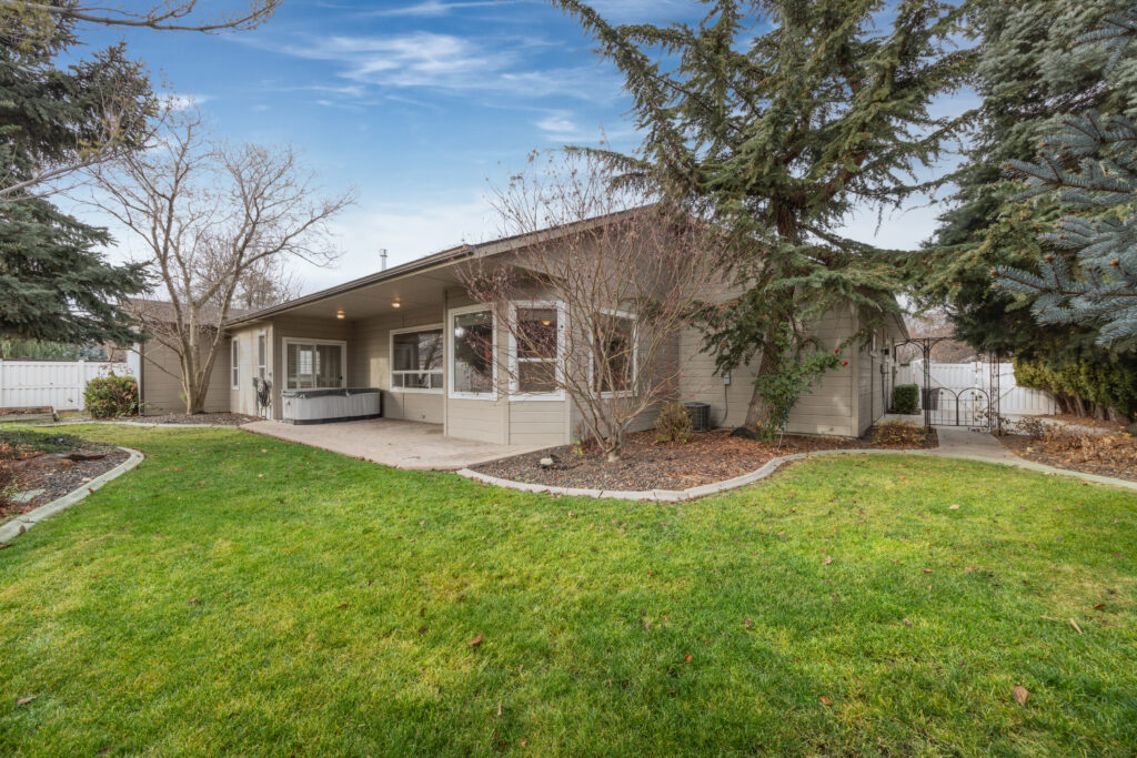 Backyard patio view featuring mature landscaping, stamped concrete patio, and hot tub at 2680 south loftus way in meridian, idaho listed by jeff sudmeier with idahoreal.estate team at action real estate.