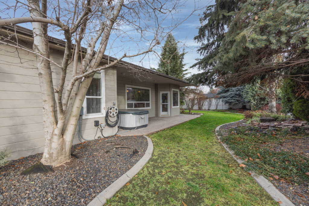 Backyard patio view featuring mature landscaping, stamped concrete patio, and hot tub at 2680 south loftus way in meridian, idaho listed by jeff sudmeier with idahoreal.estate team at action real estate.